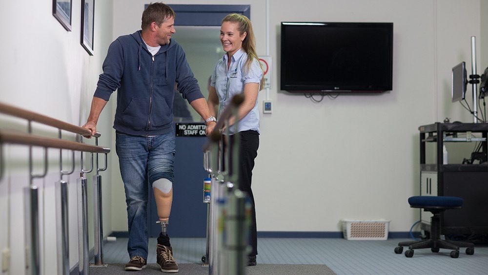 Man with prosthetic leg in rehabilitation session.
