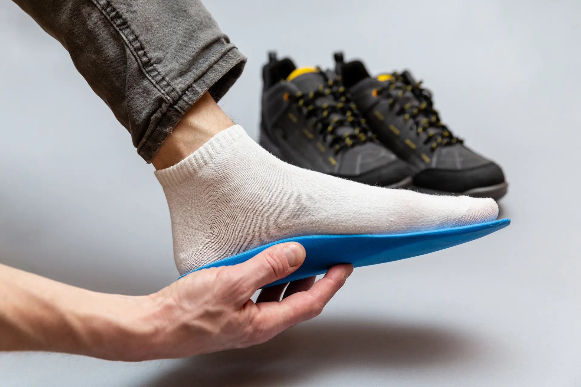 Person inserting orthotic insole into shoe
